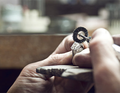 A Greenleaf & Crosby jeweler polishing a diamond ring at the bench